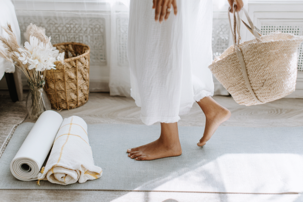 a woman holds a tote and walks towards yoga mat