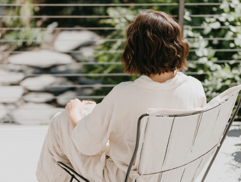 a woman lounges in a chair in an outdoor patio in a linen dress