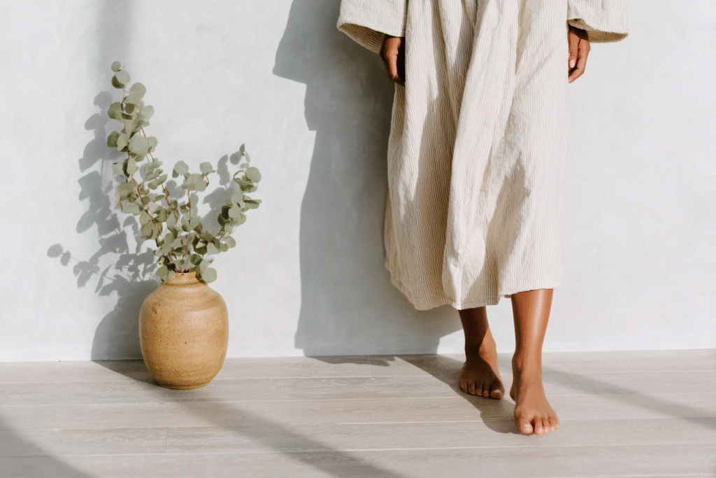 a woman standing in a robe with barefeet on a floor