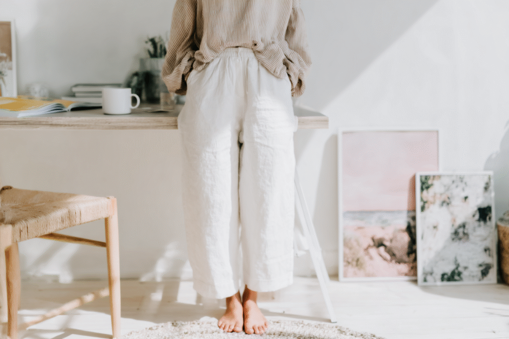 a woman stands next to her workspace in wide leg linen pants