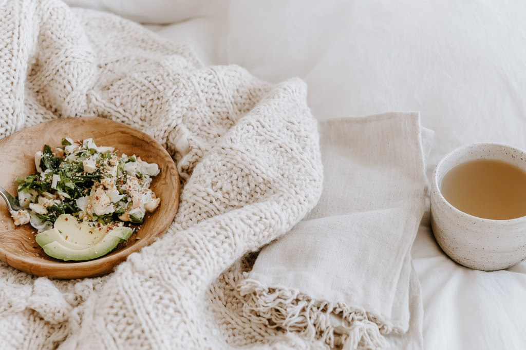 a plate of salad and mug of tea on a blanket